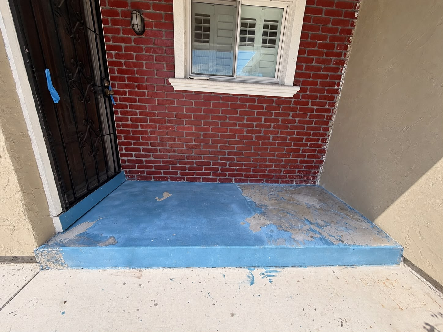 Entryway and step with peeling blue floor paint before renovation