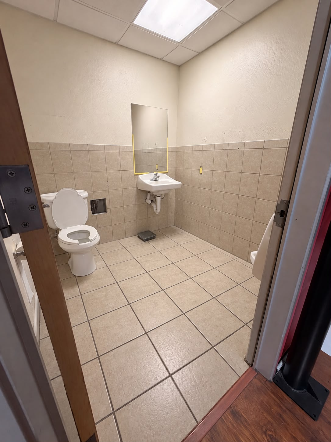 Restroom with beige tiles on the floor and lower walls before renovation